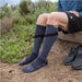 Person wearing a pair of of Injinji Trail Midweight Over the Calf – Performance Toe Socks in Granite -  gray toe-separated socks outdoors on a natural background . Buy now at ICEGRIPPER.