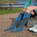 Person wearing a pair of of Injinji Trail Midweight Over the Calf – Performance Toe Socks in Storm -  blue and gray toe-separated socks outdoors by a lake. Buy now at ICEGRIPPER.