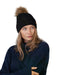 Barts Augusti beanie in black. Thie modell is wearing the  black knit beanie with a fur pom-pom on a white background.