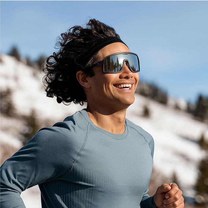 Person wearing sunglasses and a headband with a mountainous background. The Robotron Campeone is built around Knockaround’s innovative Knockterra performance lens technology, Campeone sunglasses deliver crystal-clear vision, UV400 protection, and impact-resistant durability. Their sleek wraparound design guards against low winter sun and glare reflected from snow and ice, while rubberized adjustable nose grips and flexible non-slip arms ensure a secure, all-day fit during high-energy winter pursuits.