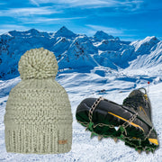 Stone Jasmine Barts Beanie, paired with ICEGRIPPER ACTIVspikes, as a special 'bundle' offer for the 2026 Milano-Cortina Winter Olympics. Both products superimposed over a snowy ski slope background.