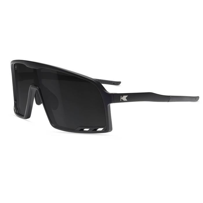 Black sunglasses with a Knockaround brand logo on a white background. Now available from ICEGRIPPER, the Knockaround Campeone Black on Black combines advanced performance technology with rugged outdoor style — ideal for trail runners, winter hikers, mountain trekkers, and polar explorers who demand comfort and clarity in challenging light conditions. Buy now at ICEGRIPPER.