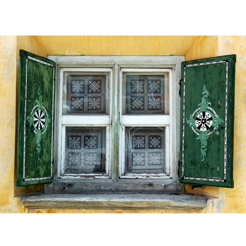 Antique shuttered window with green shutters on a yellow walltique. Typical of what you will find in the Engadine, Switzerland